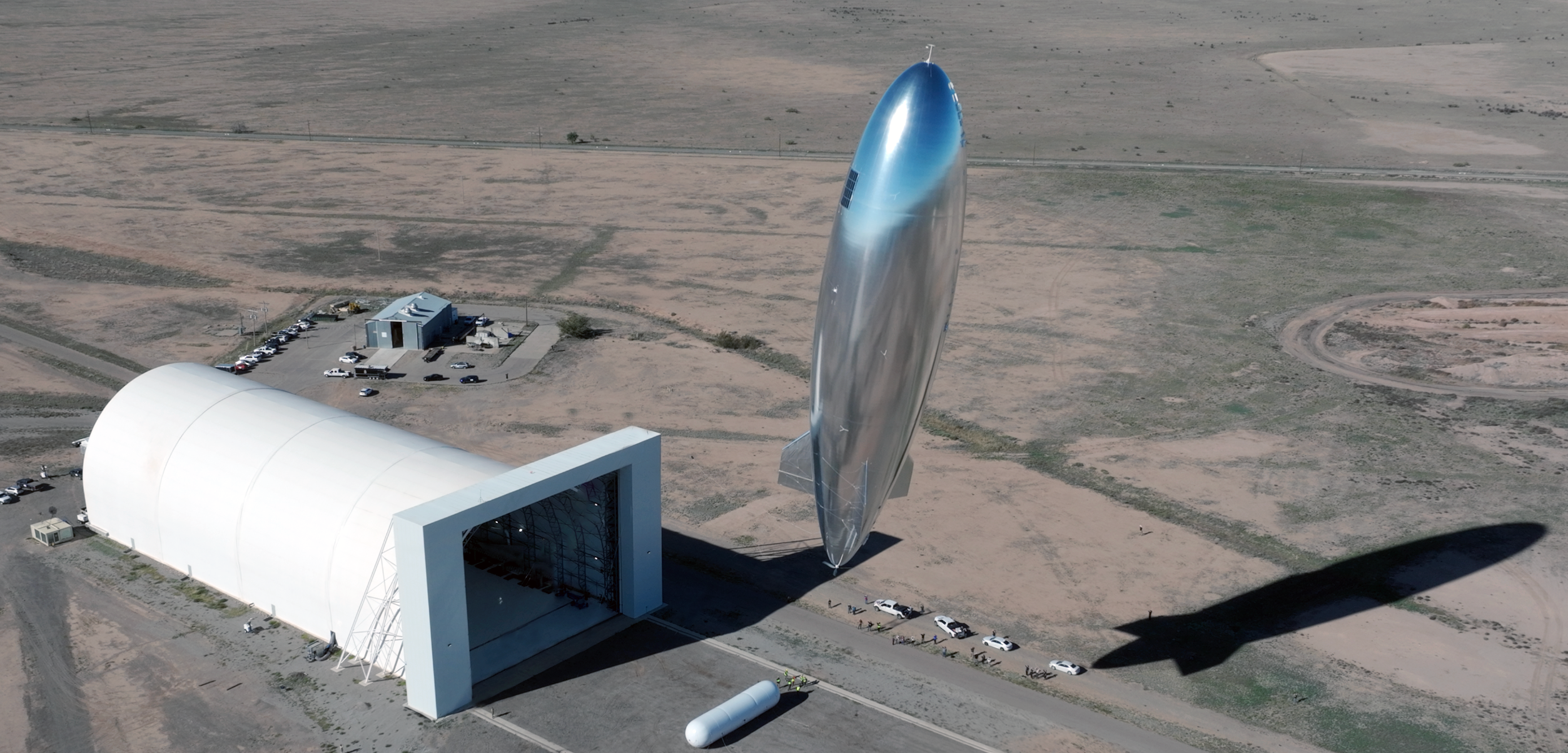 A silvery blimp shape satellite seems to float above the desert of New Mexico