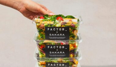 three salads in plastic containers with black labels stacked on top of each other