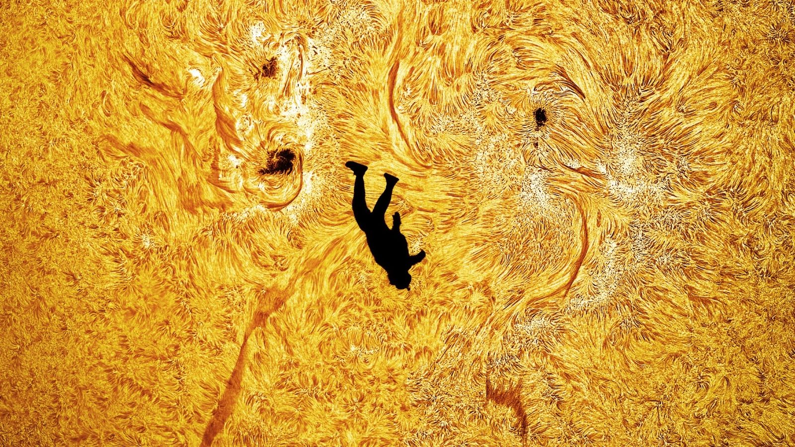 A close up image of the silhouette of a skydiver against the fiery surface of the sun