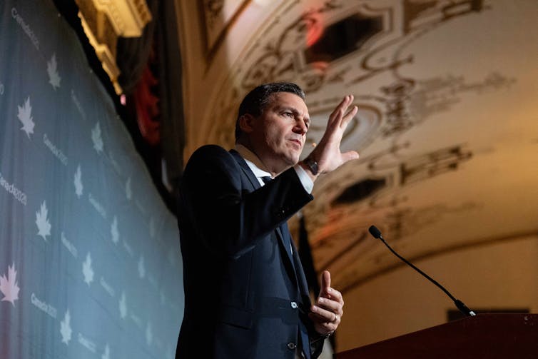 A man in a suit speaks from behind a podium