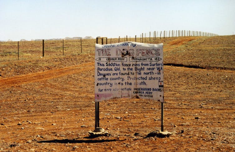 A white sign in the middle of a red desert.