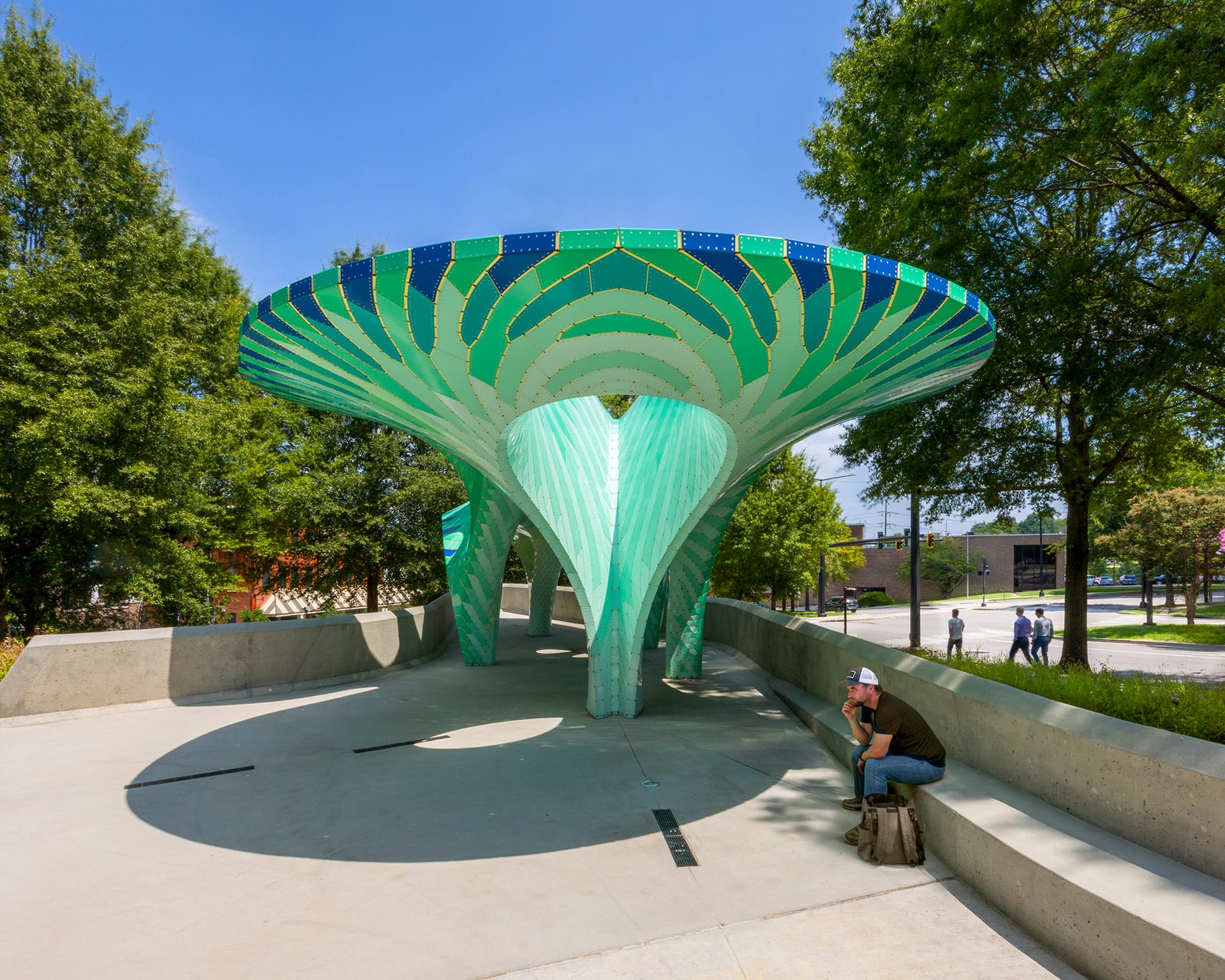a contemporary, teal-colored pavilion designed by Marc Fornes/THEVERYMANY in a public square in Knoxville, Tennessee