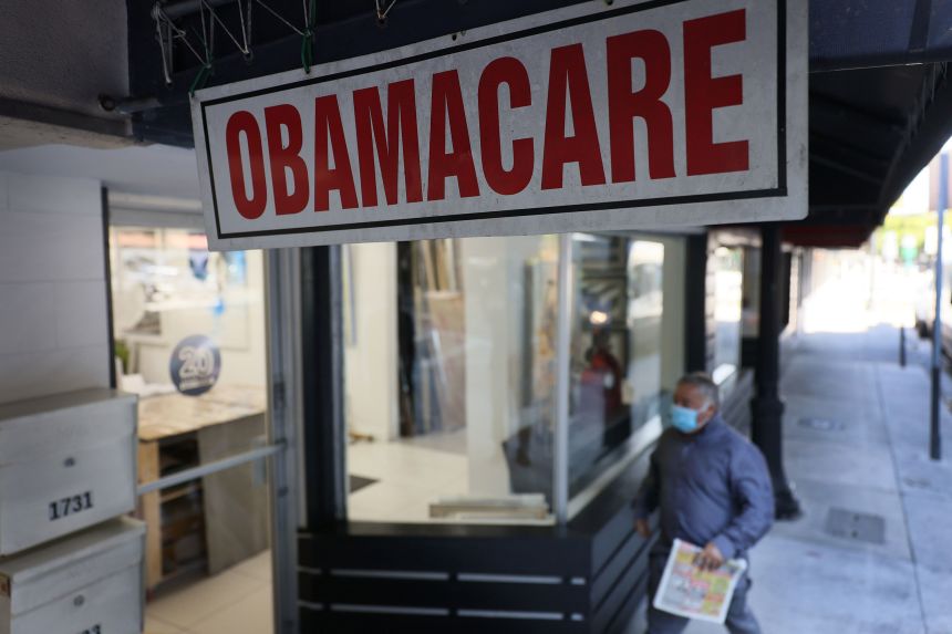 A pedestrian walks past the Leading Insurance Agency, which offers plans under the Affordable Care Act, on January 28, 2021, in Miami, Florida.