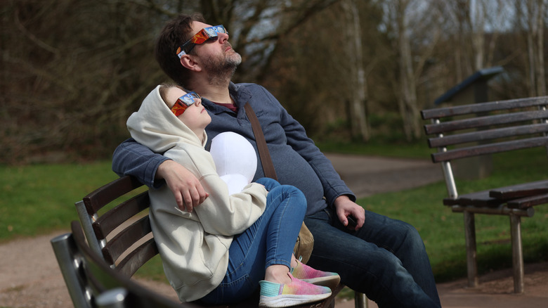 Father and daughter watching a solar eclipse.