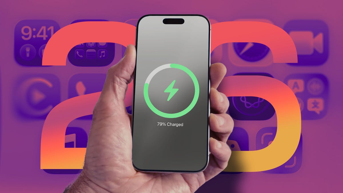 A hand holds an iPhone with a battery charging status in front of the number "26" and application icons in the background.