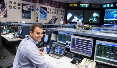 A man wearing a headset sits at a computer console in the Mission Control Center at Johnson Space Center.