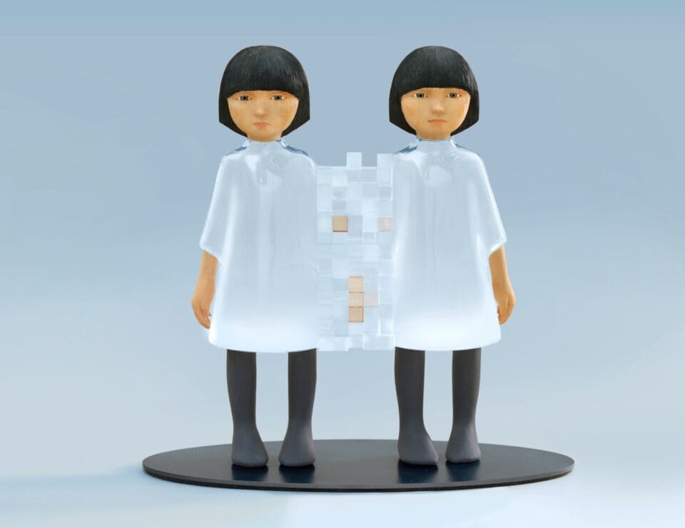a small sculpture by Ayako Kita made of cypress and acrylic resin, depicting two female figures connected via a three-dimensional pixellation