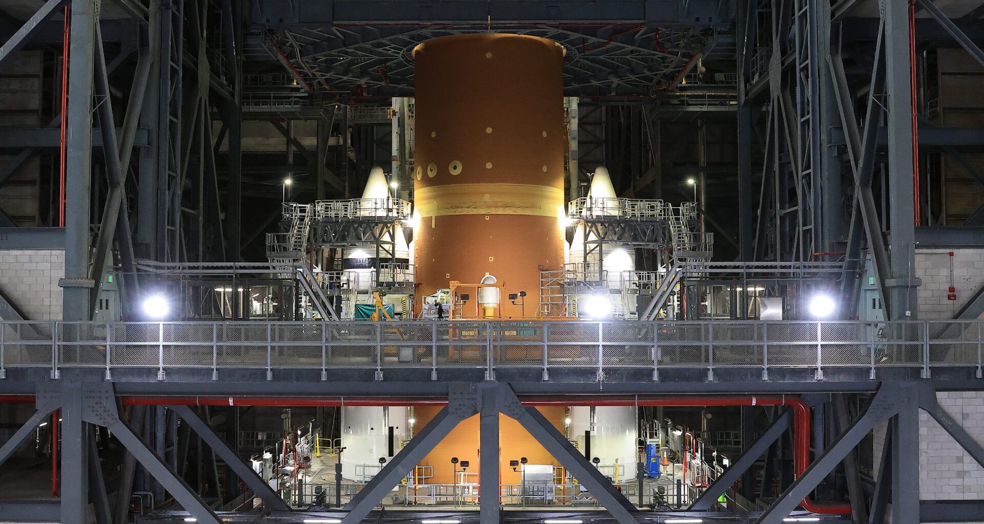 The orange core stage of the Artemis II rocket with white boosters on each side fully stacked inside the Vehicle Assembly Building at NASA's Kennedy Space Center in Florida on Saturday, Oct. 18, 2025.