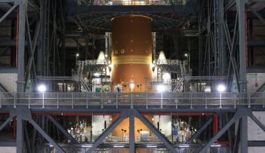 The orange core stage of the Artemis II rocket with white boosters on each side fully stacked inside the Vehicle Assembly Building at NASA's Kennedy Space Center in Florida on Saturday, Oct. 18, 2025.