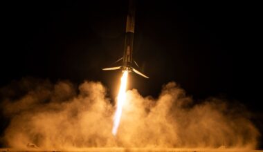 A rocket blazes up into a night time sky with glowing orange clouds of smoke illuminated by the tail of the rocket in the night