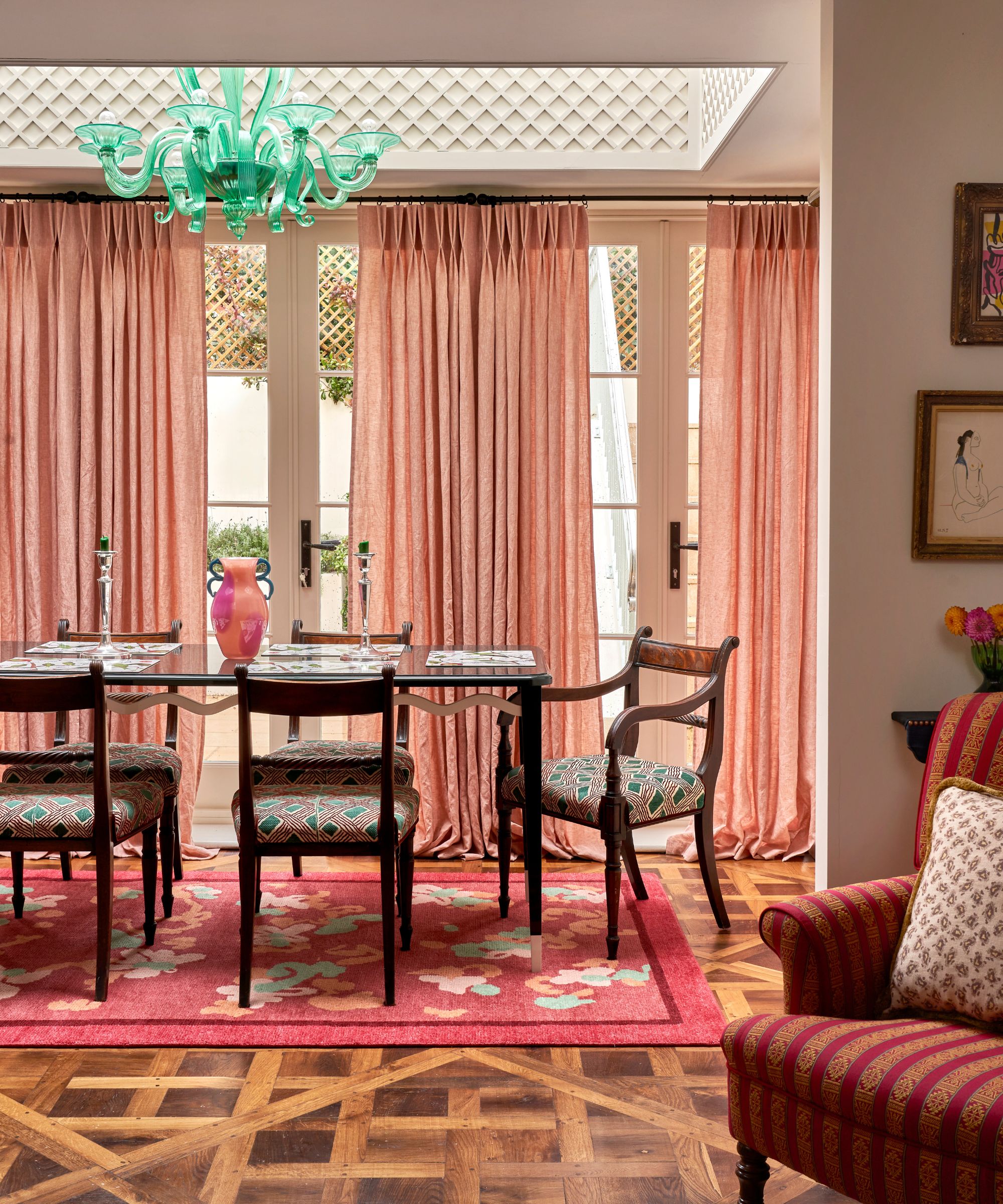 dark wood flooring in a dining room orangery room with pink drapes and an antique table and chairs with sea green sculptural chandelier