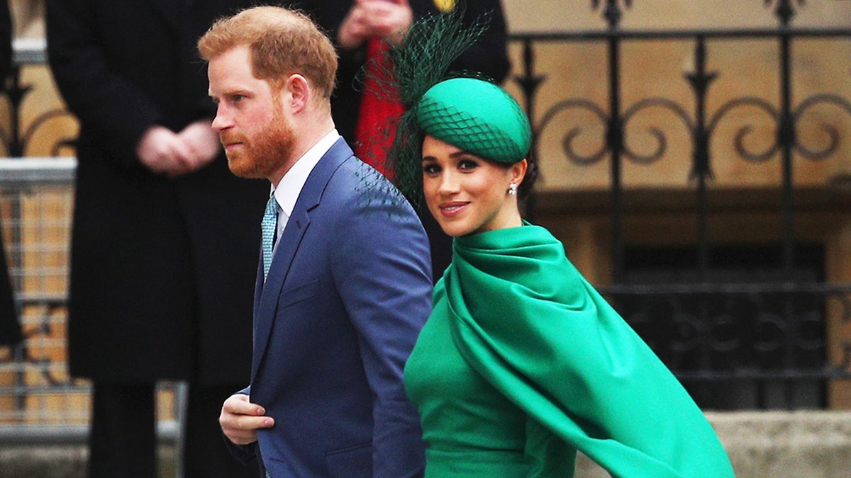 Meghan Markle in a green dress in the arm of Prince Harry