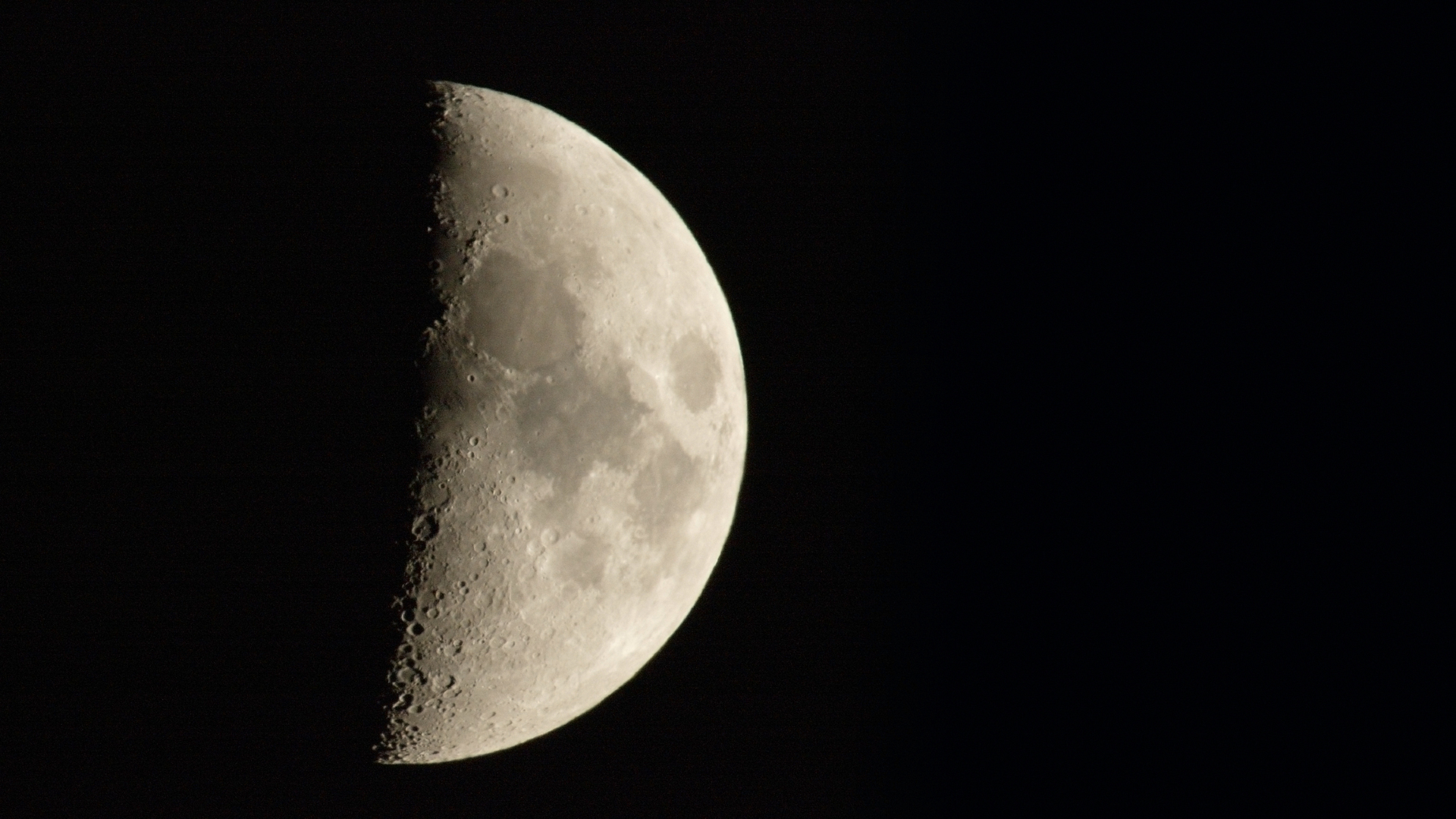 A close up of the moon in space with only its right side illuminated