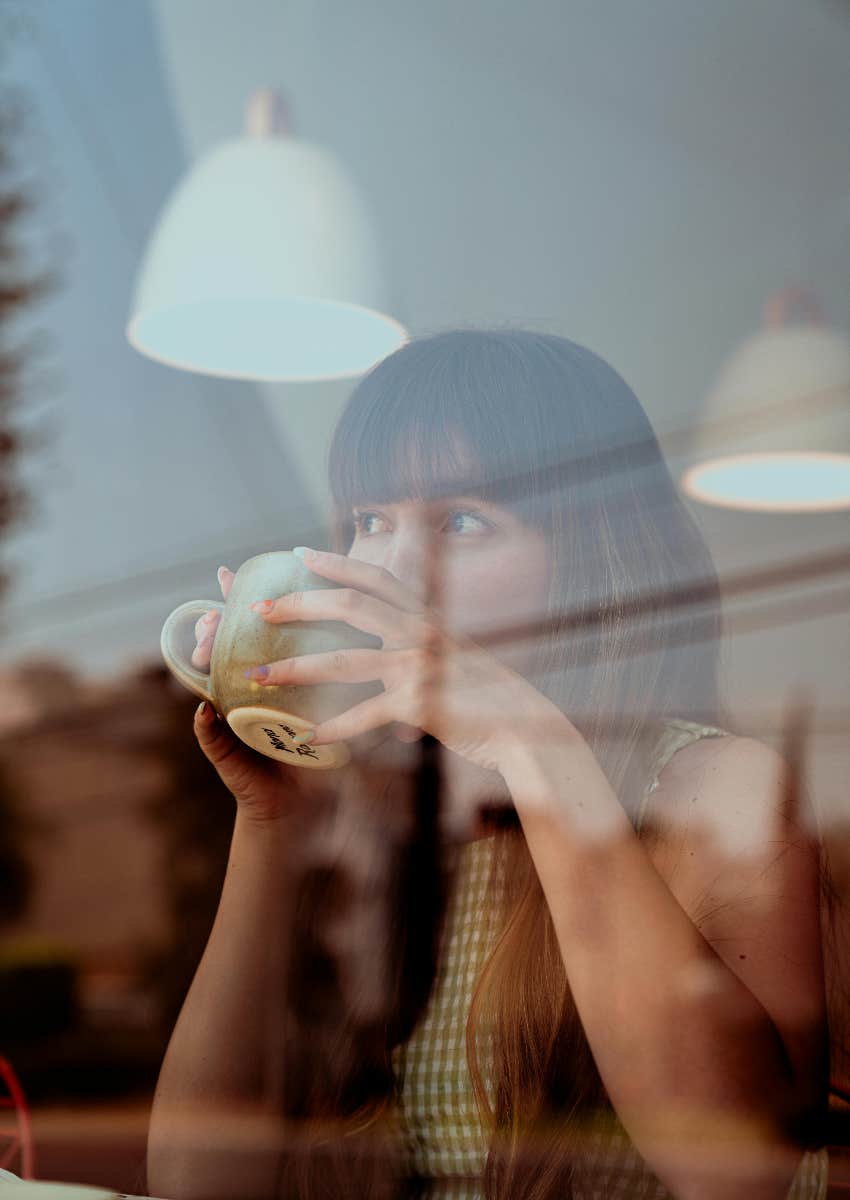 woman drinking a cup of coffee she spent extra on