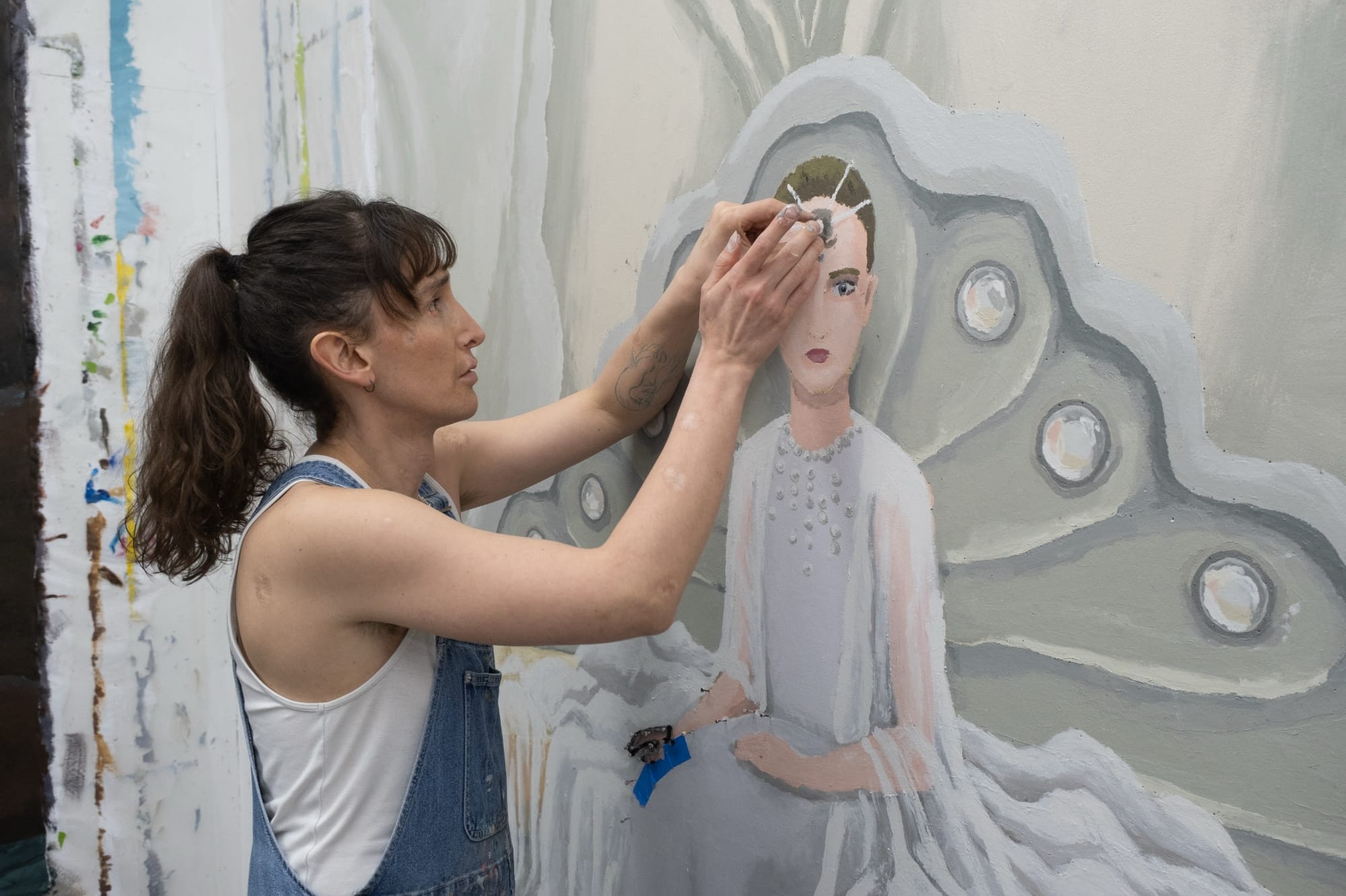 the artist works on a portrait of a woman in white through touch