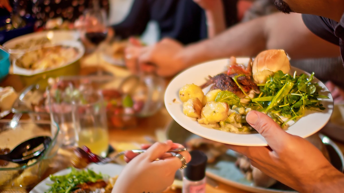 Man loading Thanksgiving plate with greens, meat