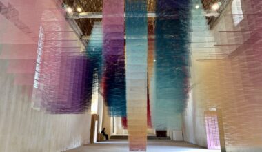 an art installation by Tomislav Topić of layers of colorful planes of fabric suspended from the ceiling in undulating rows so that it looks prismatic