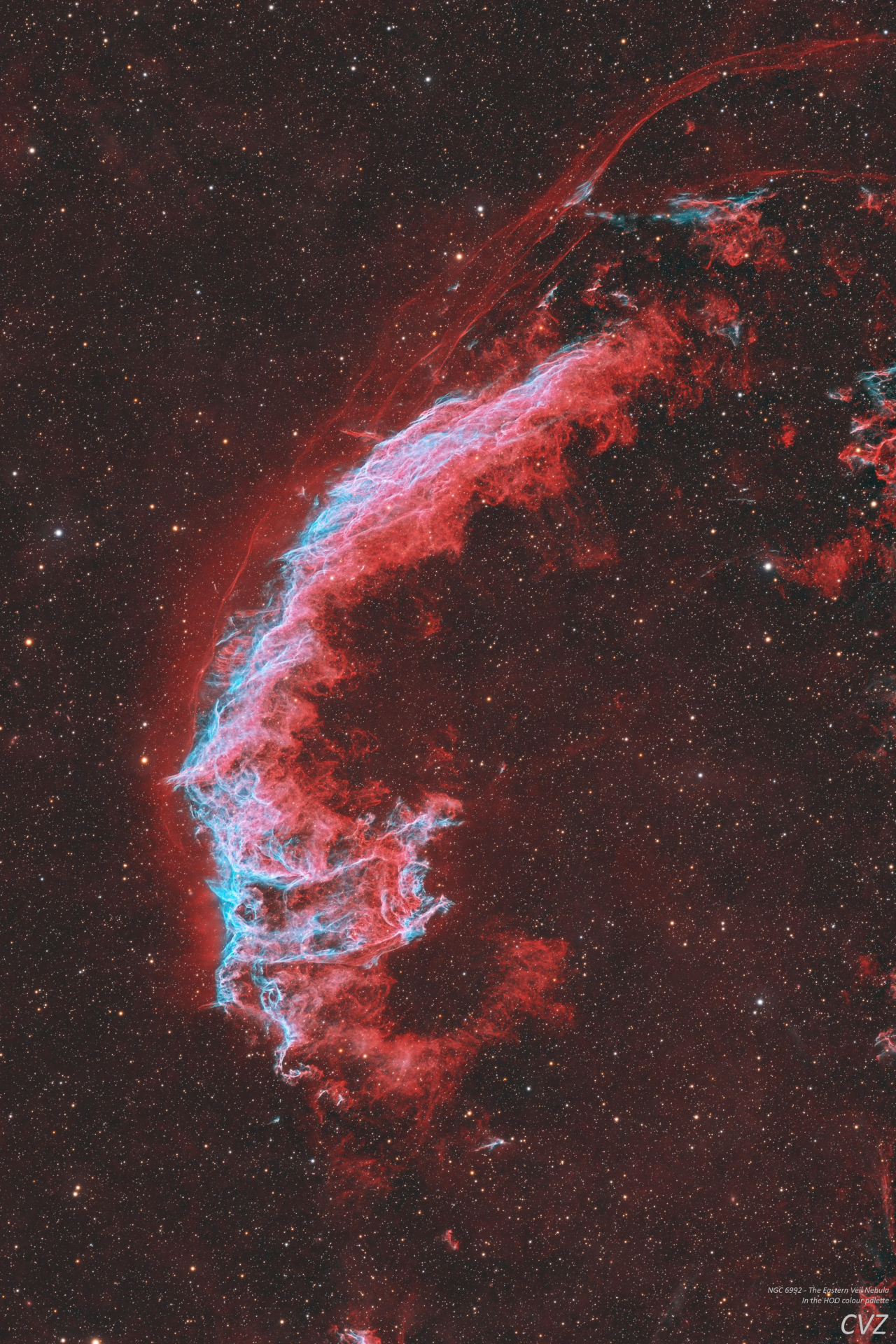 A swirling red nebula is pictured against a distant starfield