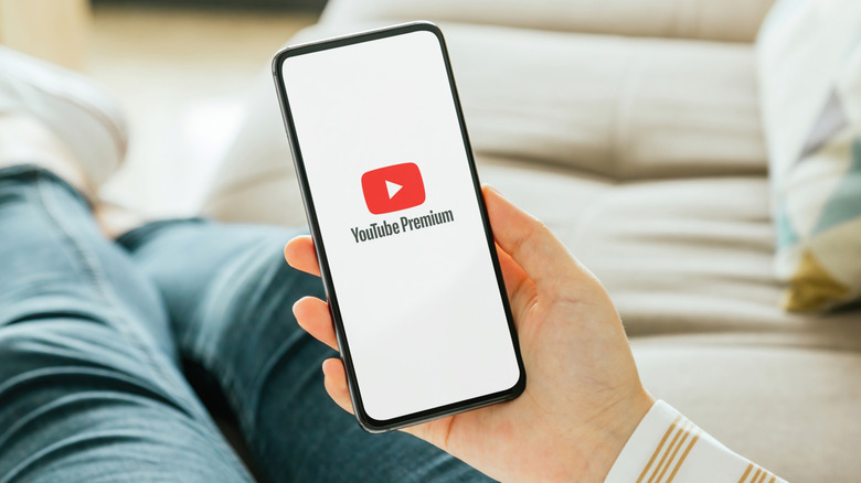 Person holding a phone showing the YouTube Premium logo on the screen