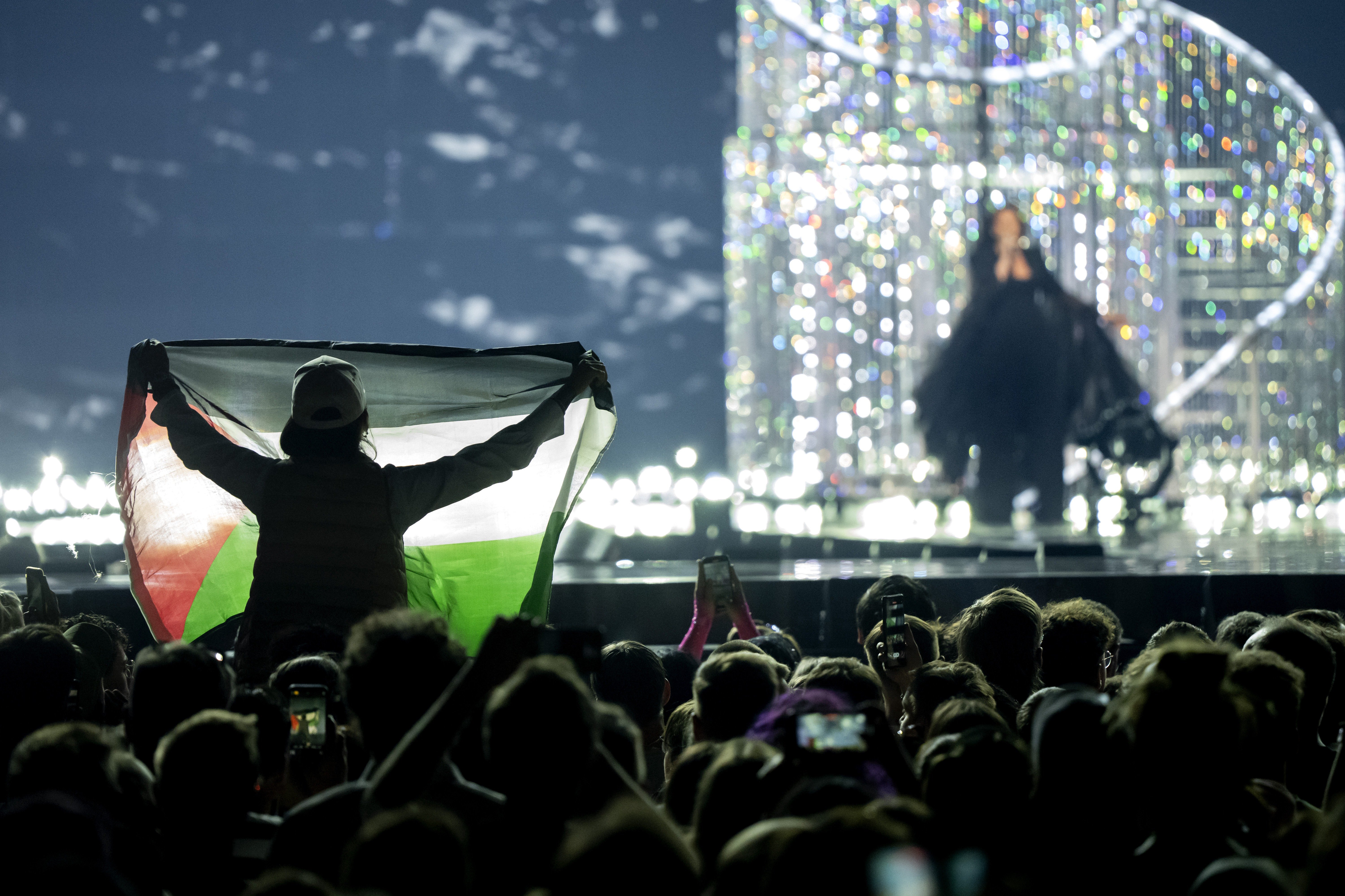 A visitor holds a Palestinian flag during a performance by Yuval Raphael for Israel during a dress rehearsal for the Eurovision Song Contest.