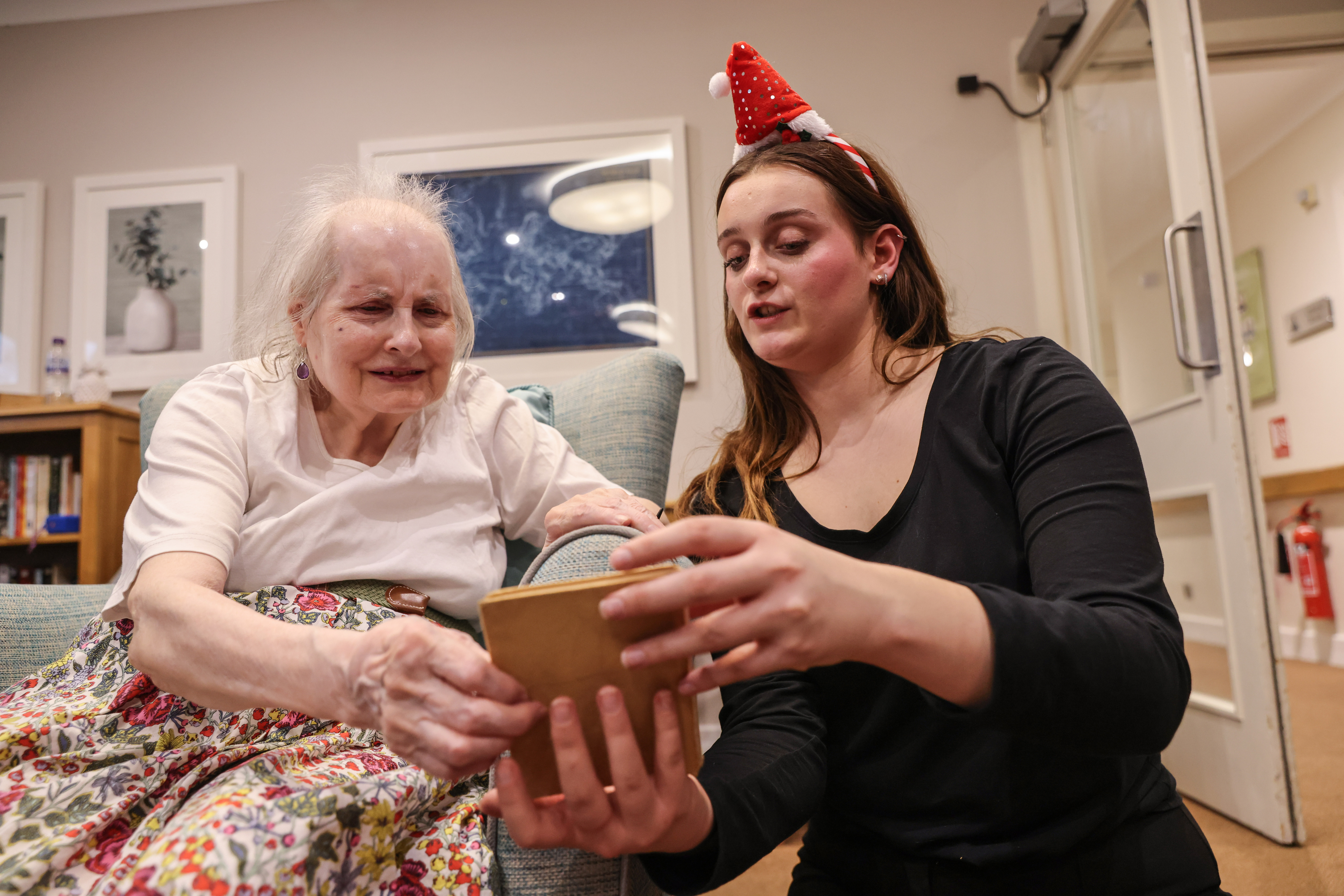 Volunteer Alexi Prati and resident Helen Bright-Chard look at comics and games at Cheverton Lodge Care Home.