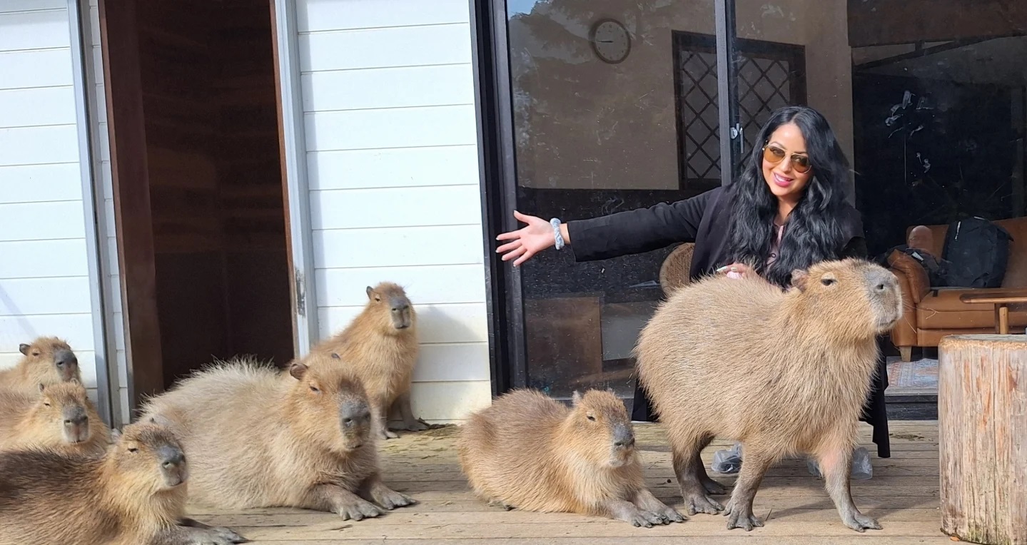 Sharon Walia filming for "The Route to Cappiness" documentary surrounded by capybaras.
