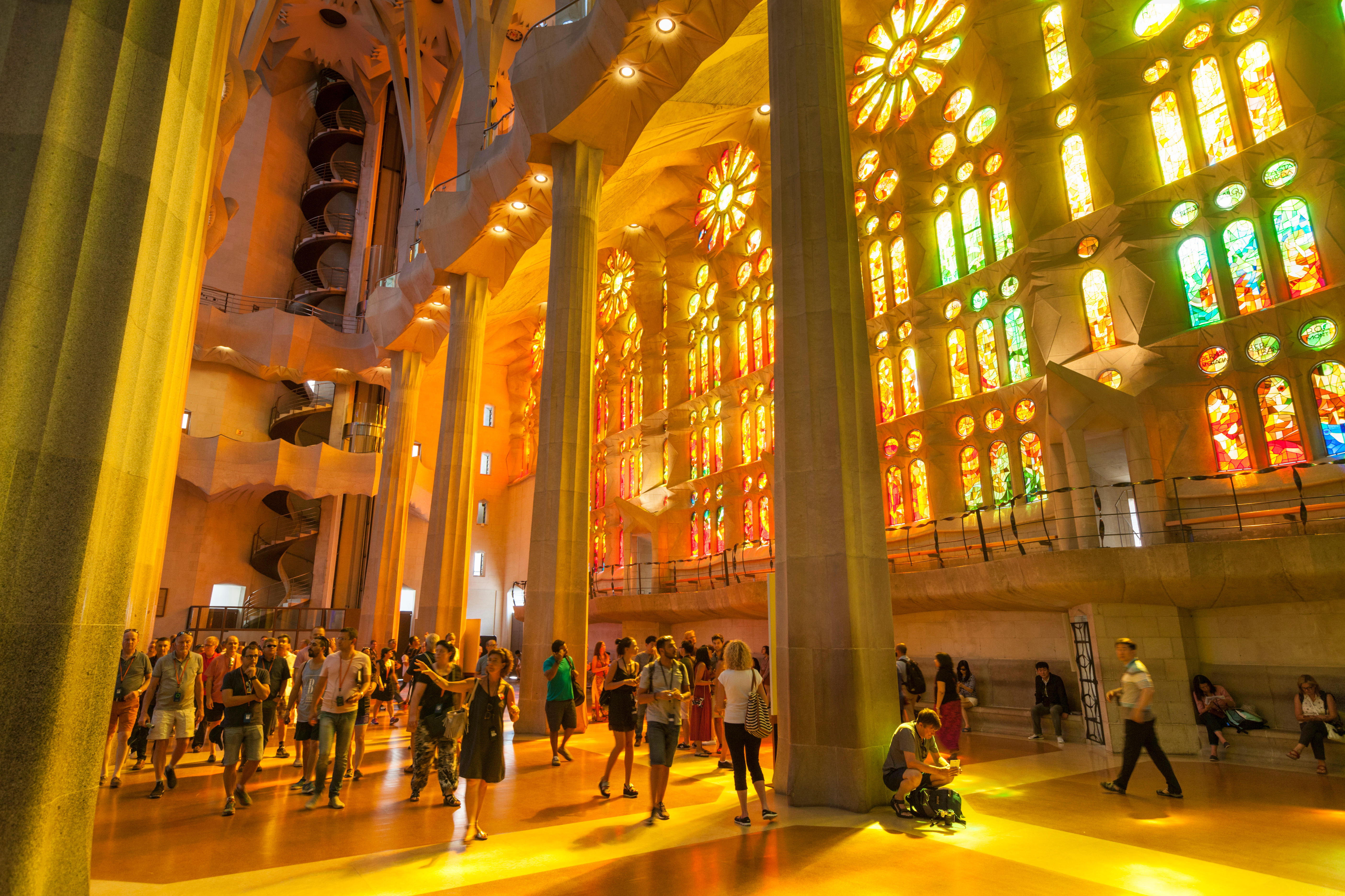 La Sagrada Familia church interior with stained glass windows by Antoni Gaudi and tourists.