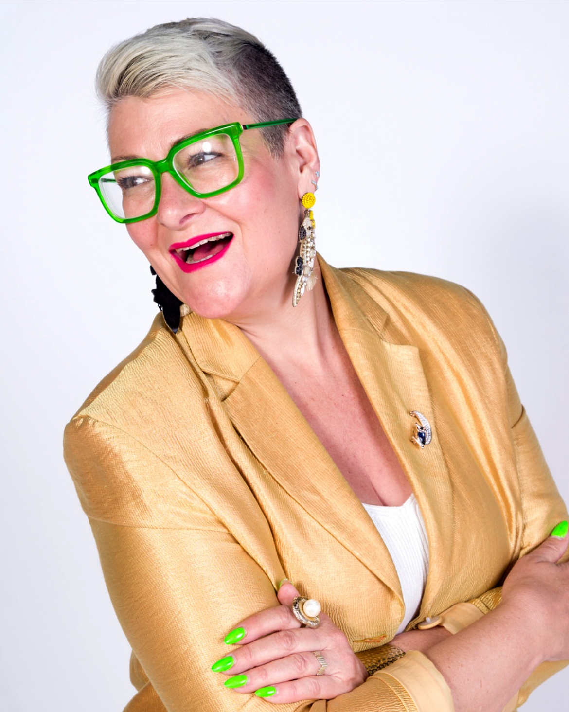 Abbey Booth in a gold jacket, bright green glasses, and neon green nails.