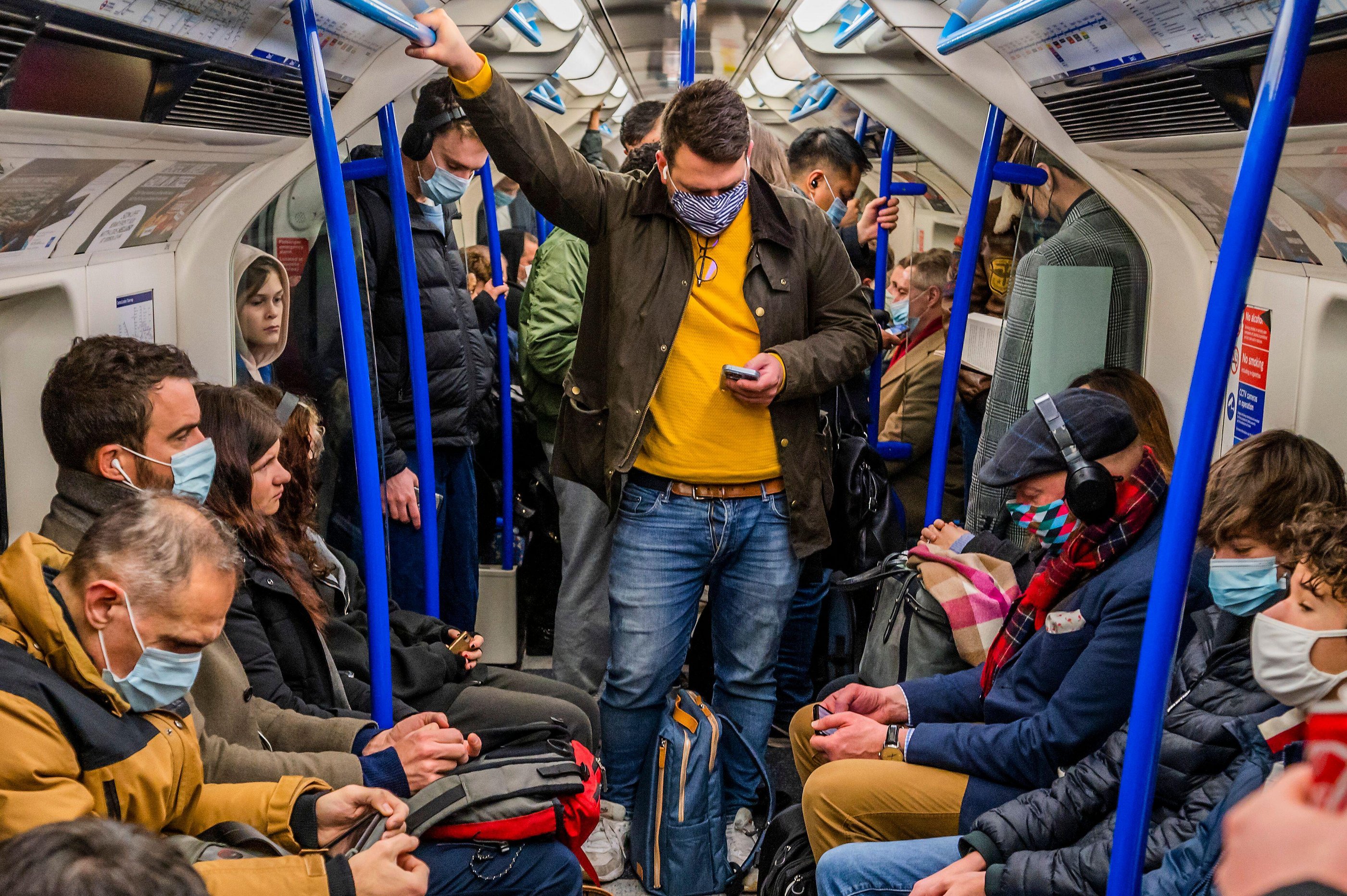 People on a London Underground train, most wearing masks.