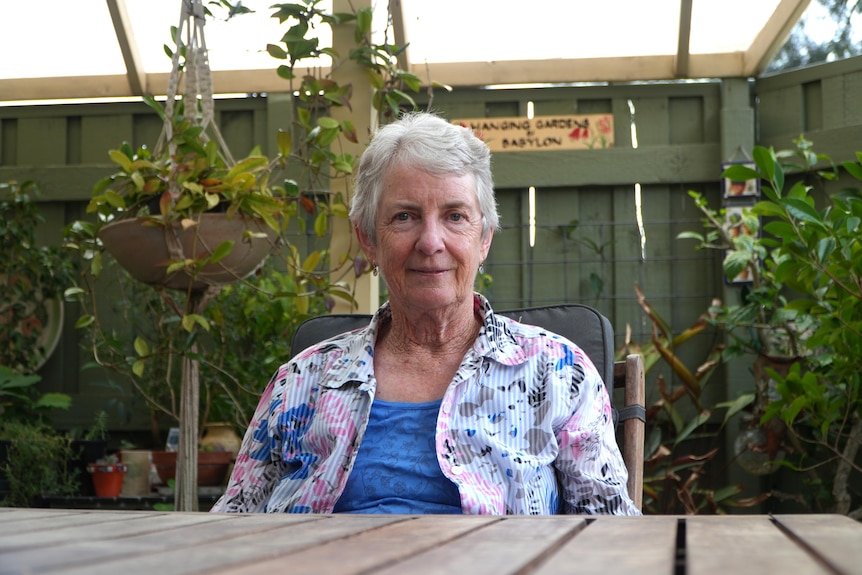 A woman with white hair sits at a table. 