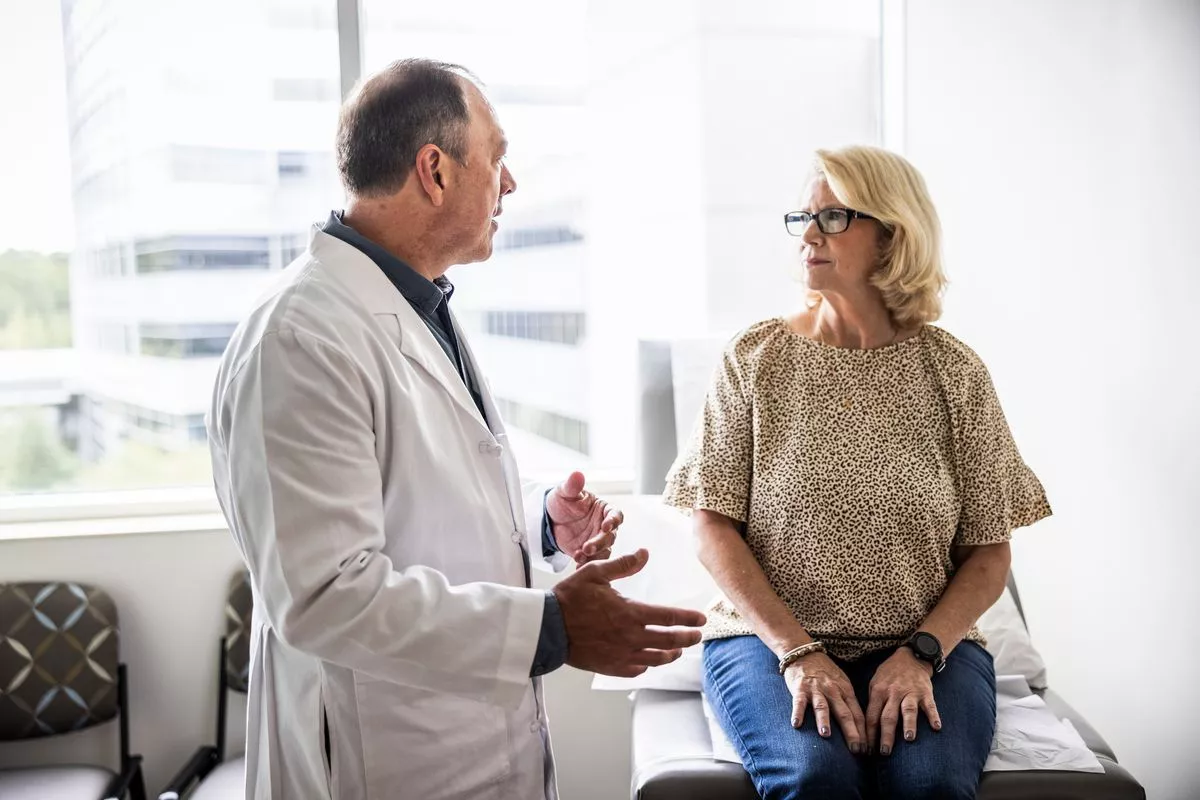 Senior male doctor consulting with senior woman in exam room