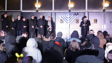 Reuters Rabbi Daniel Walker speaks during a menorah lighting ceremony on the second night of Hanukkah at Heaton Park Synagogue, the site of October's deadly shooting, in Manchester.