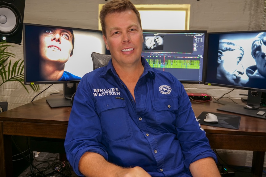 A man sits in front of his computer workspace.