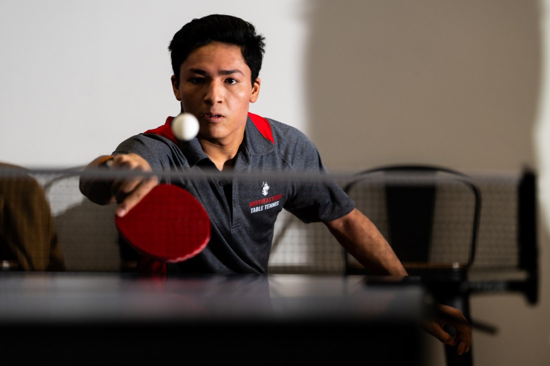 A table tennis ball sails over the net as Caden Caver sets up to return it.
