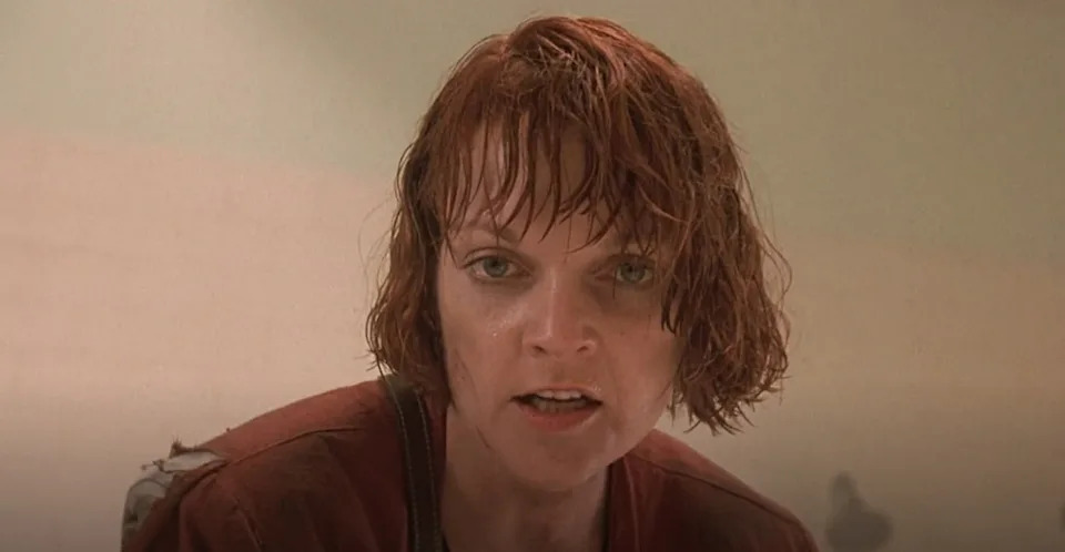 A character with disheveled hair and a determined expression, wearing a casual outfit, appears to be in an intense scene