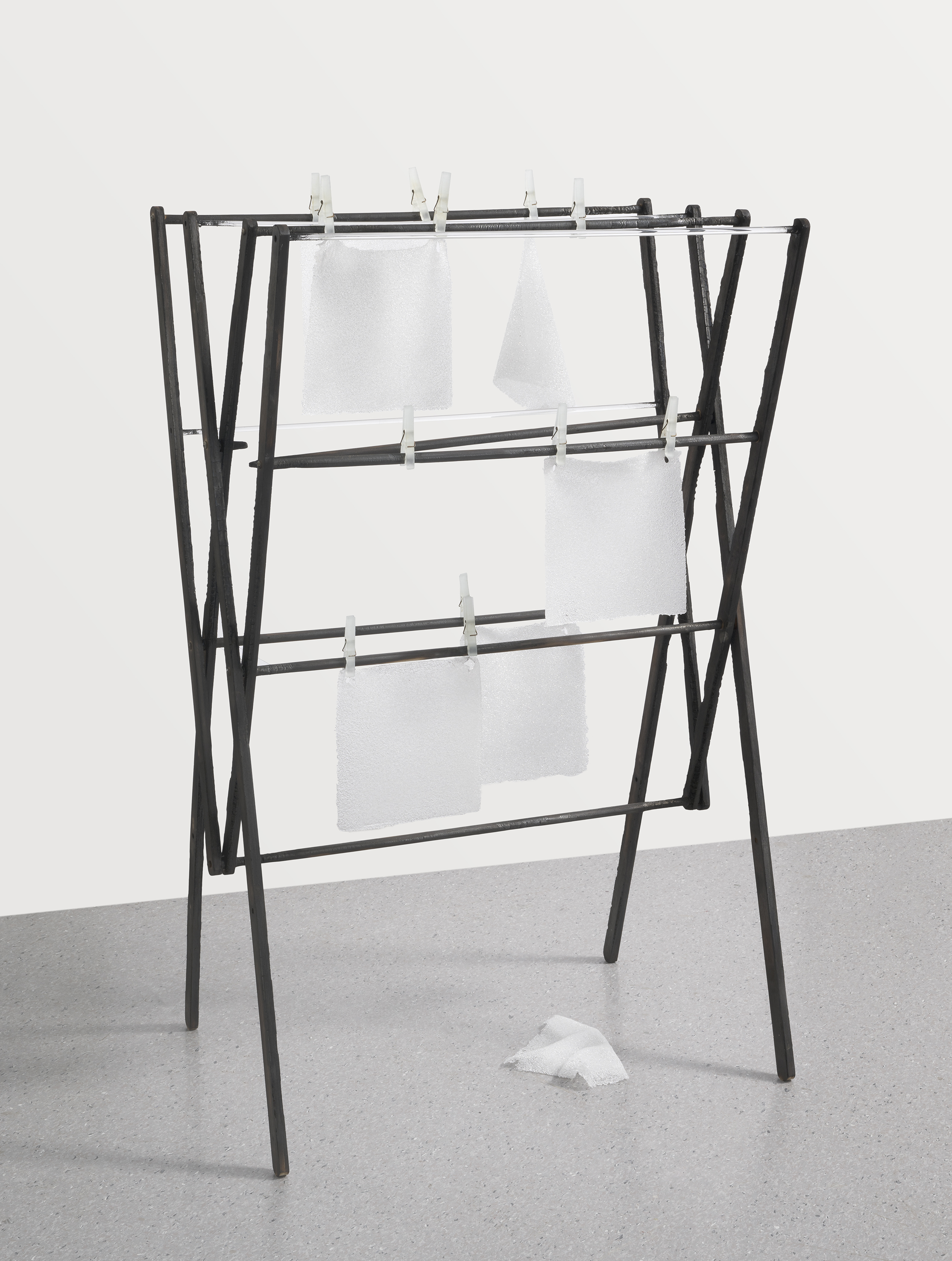 A black clothes dryer with four squares of glass 'fabric' looking like they are hung out to dry as laundry.