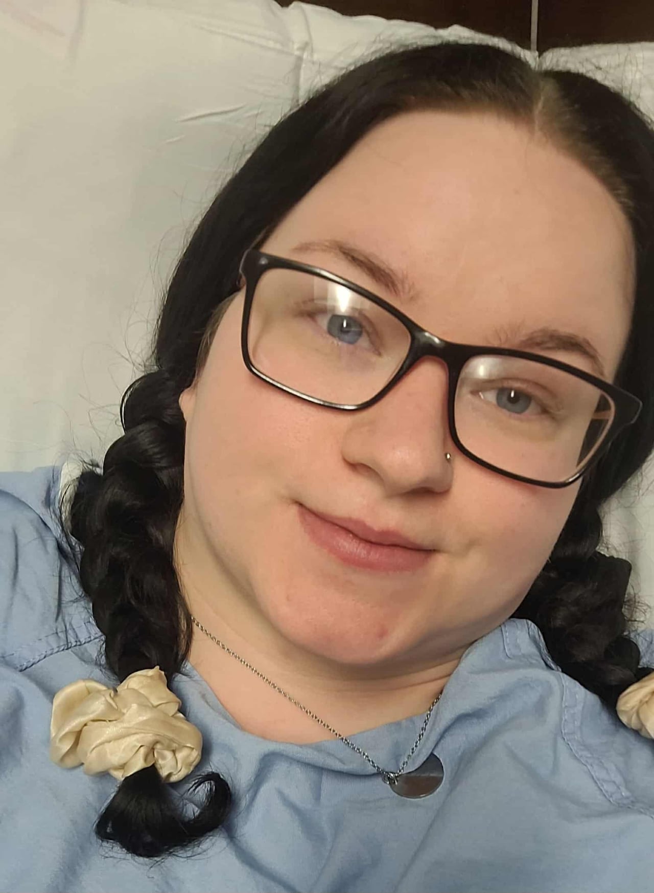 A brunette in a hospital gown takes a selfie