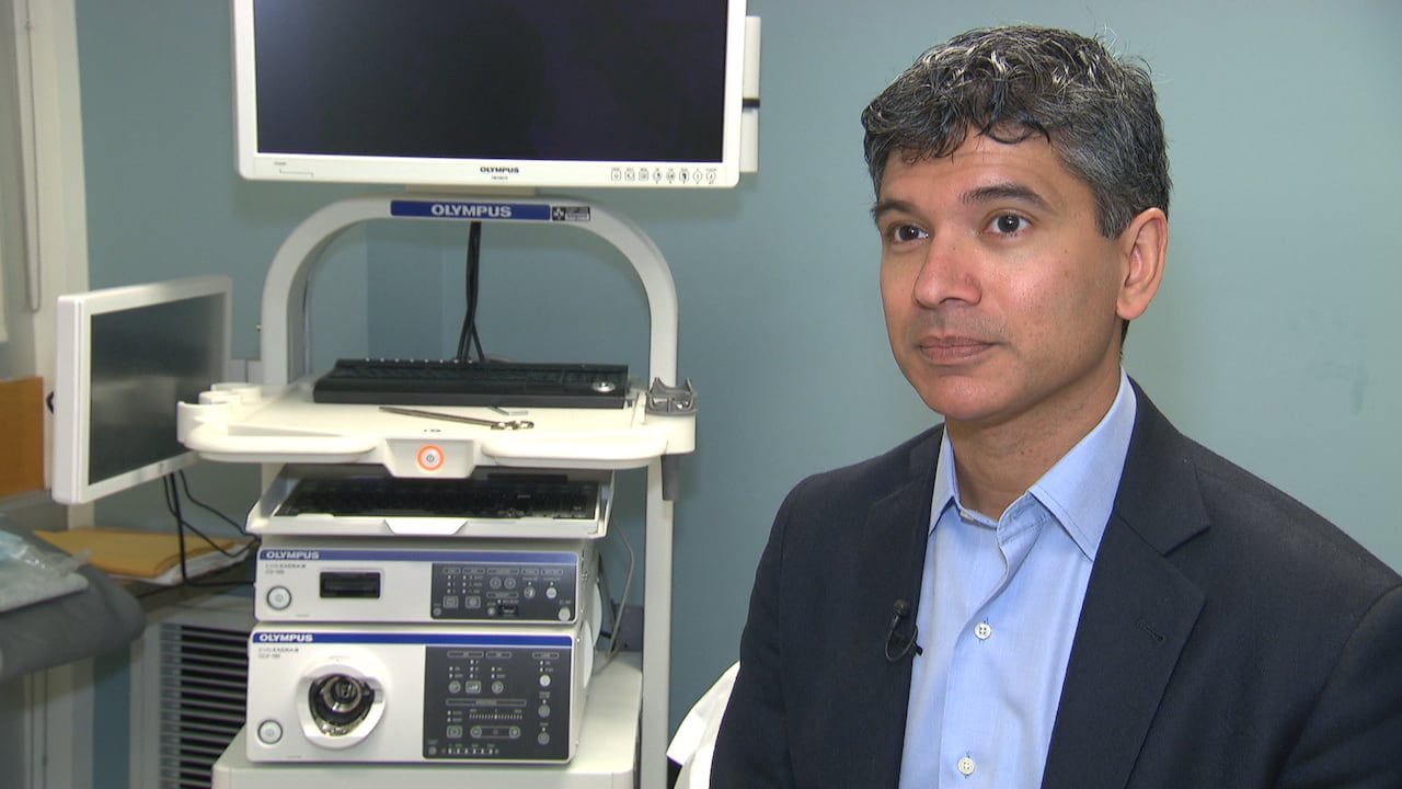 A man in a blue suit sits in front of a medical machine. 