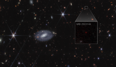 Webb image shows hundreds of galaxies of all shapes and sizes against the black background of space. Toward the center-right is a large box that zooms in to show a faint red dot with the label GRB 250314A.