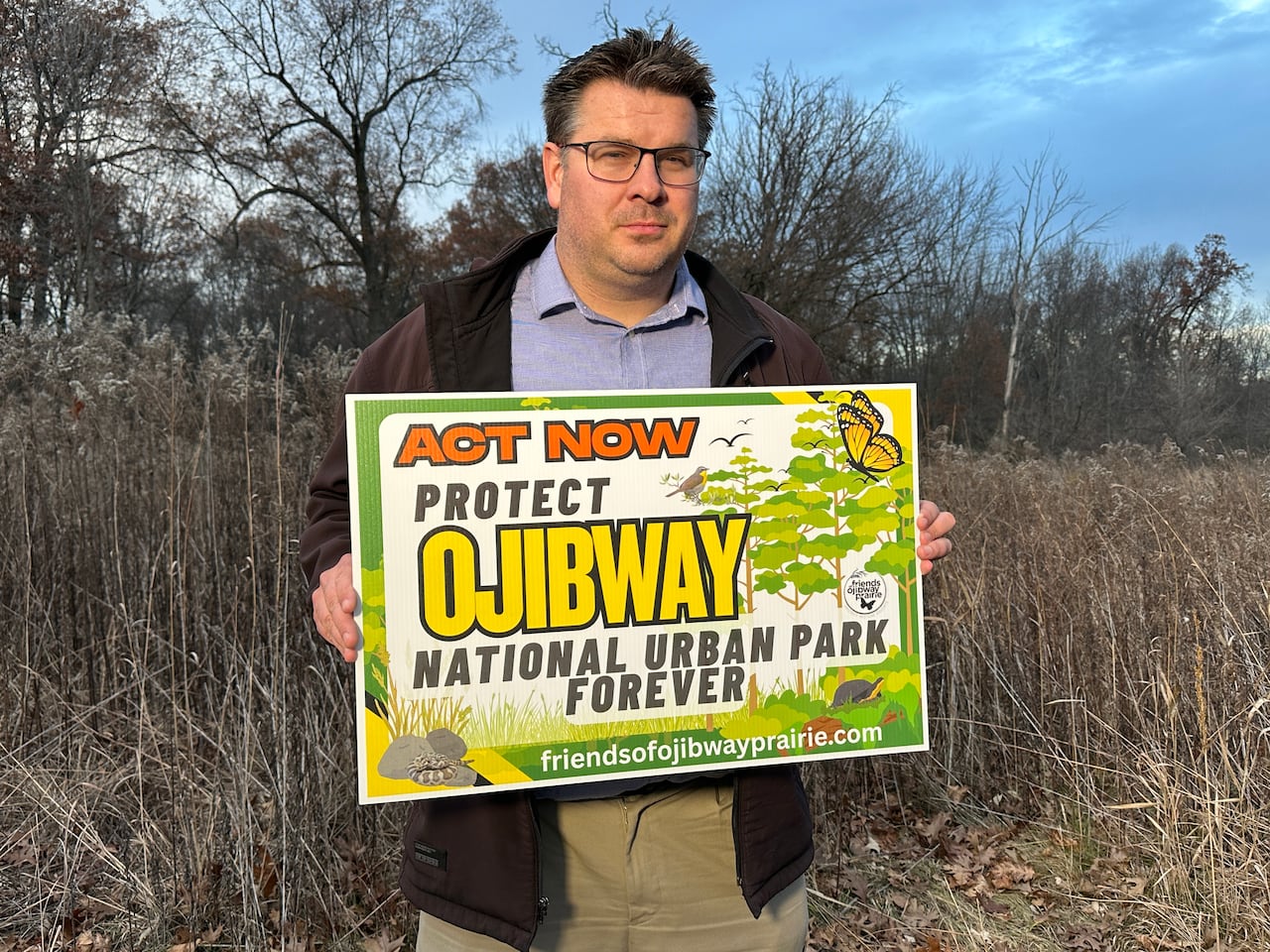 A man in a natural park area holds an advocacy sign.