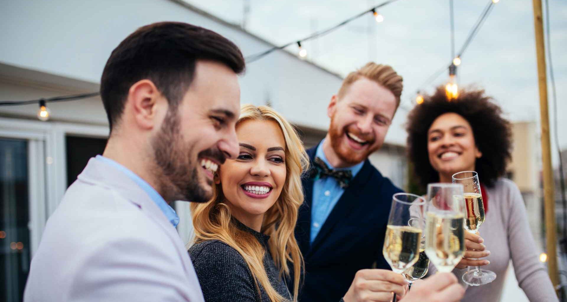 A group of wealthy friends smile as they drink champagne and enjoy the rich life.