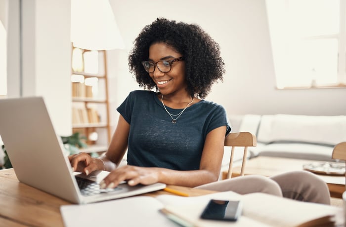 An investor smiles while working on a laptop.