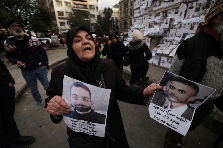A Syrian woman holds up posters showing her missing sons.