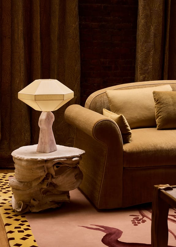 Elegant living room with brown sofa, cozy pillows, geometric lamp on artistic side table, and decorative patterned curtains.