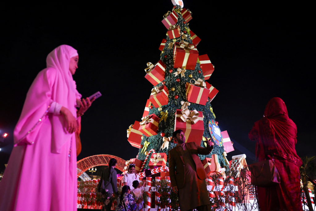 A man poses for pictures near a Christmas tree in Dubai