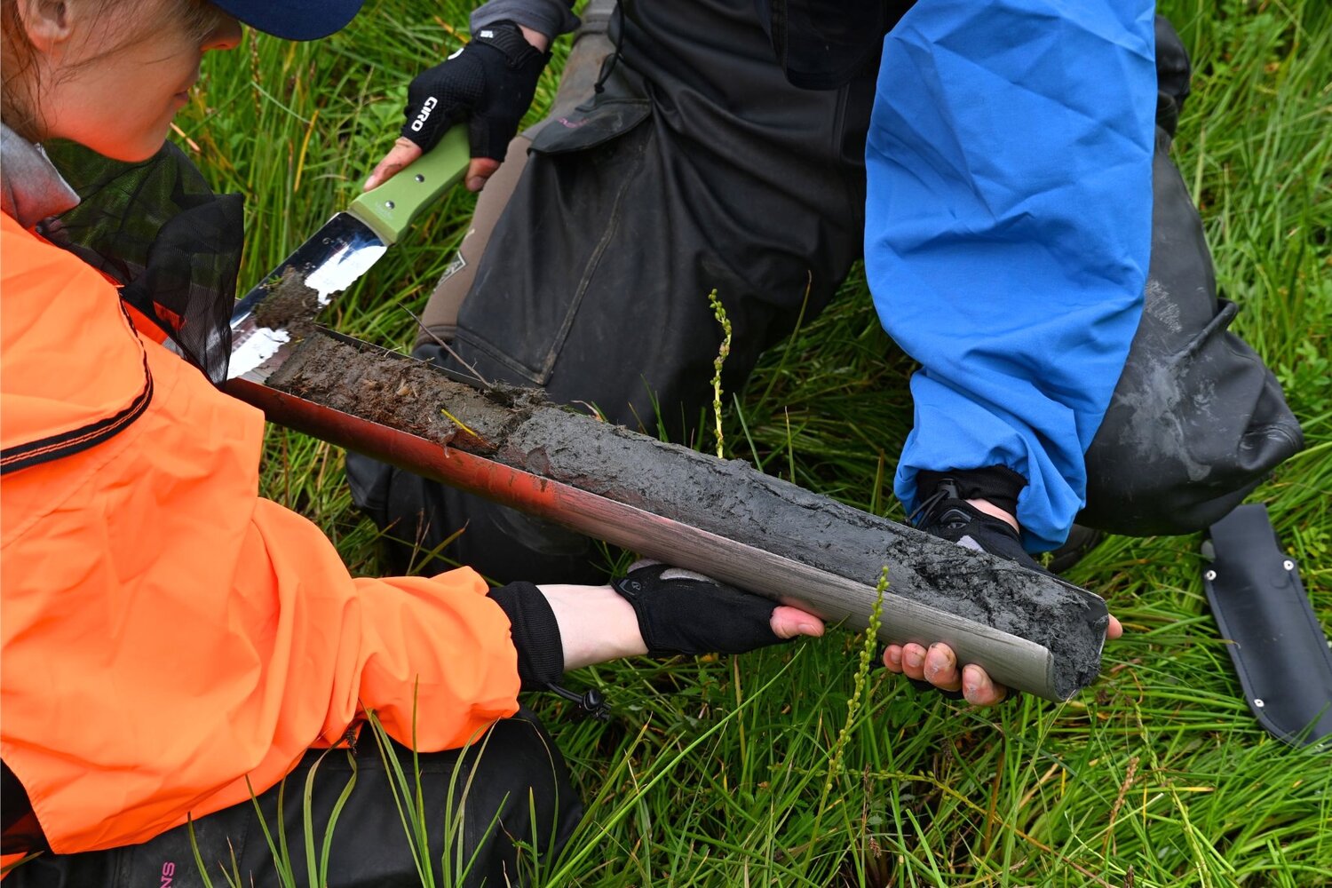 Scientists from URI examine layers of organic matter in a sediment core they collected from a salt marsh. (Photo courtesy of Sophia Wensman)