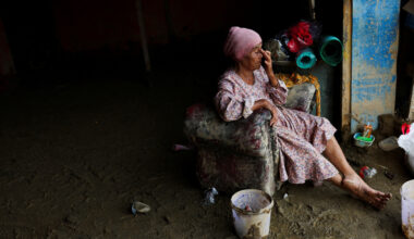 Survivor Rosmaniah Nasution, 70, sits as she takes a break while collecting valuable goods from her grocery shop that was heavily damaged following a deadly flash flood in Batang Toru, South Tapanuli, North Sumatra, December 6, 2025.