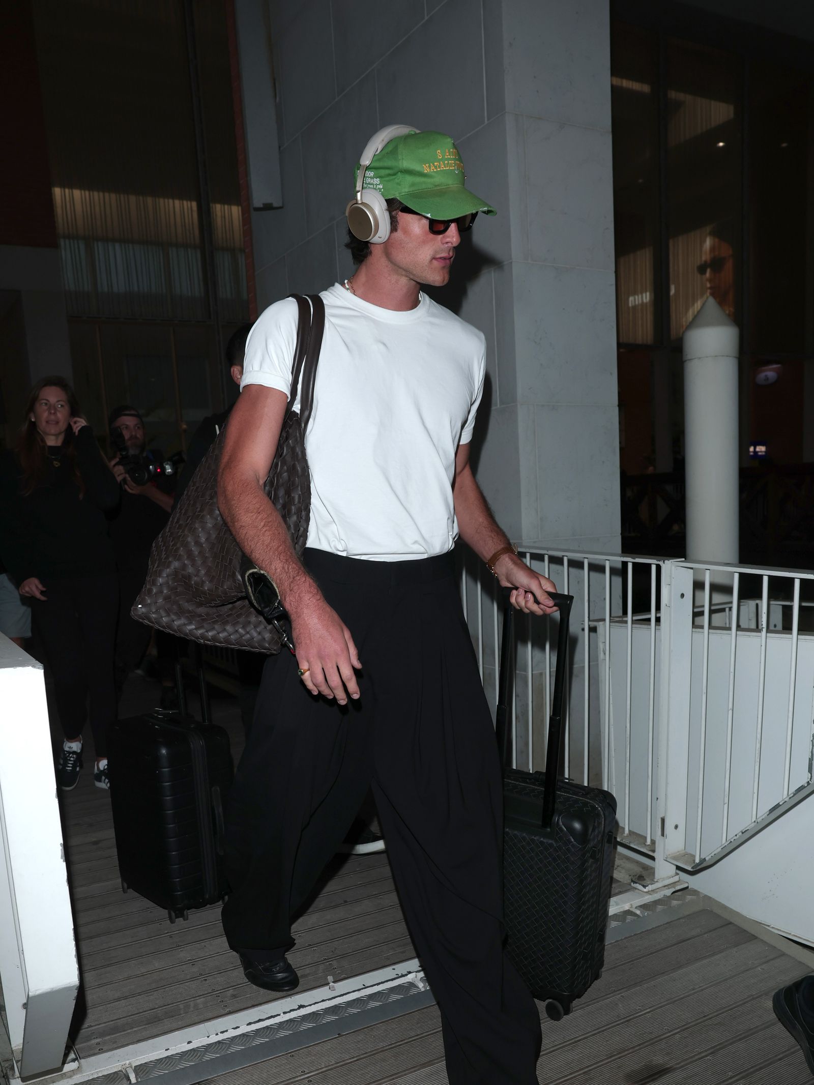 Image may contain Glen Powell Clothing Hat Adult Person Baseball Cap Cap Electronics Headphones Footwear and Shoe