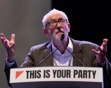Jeremy Corbyn stands behind a lectern with a red triangle that says 'This is your party'
