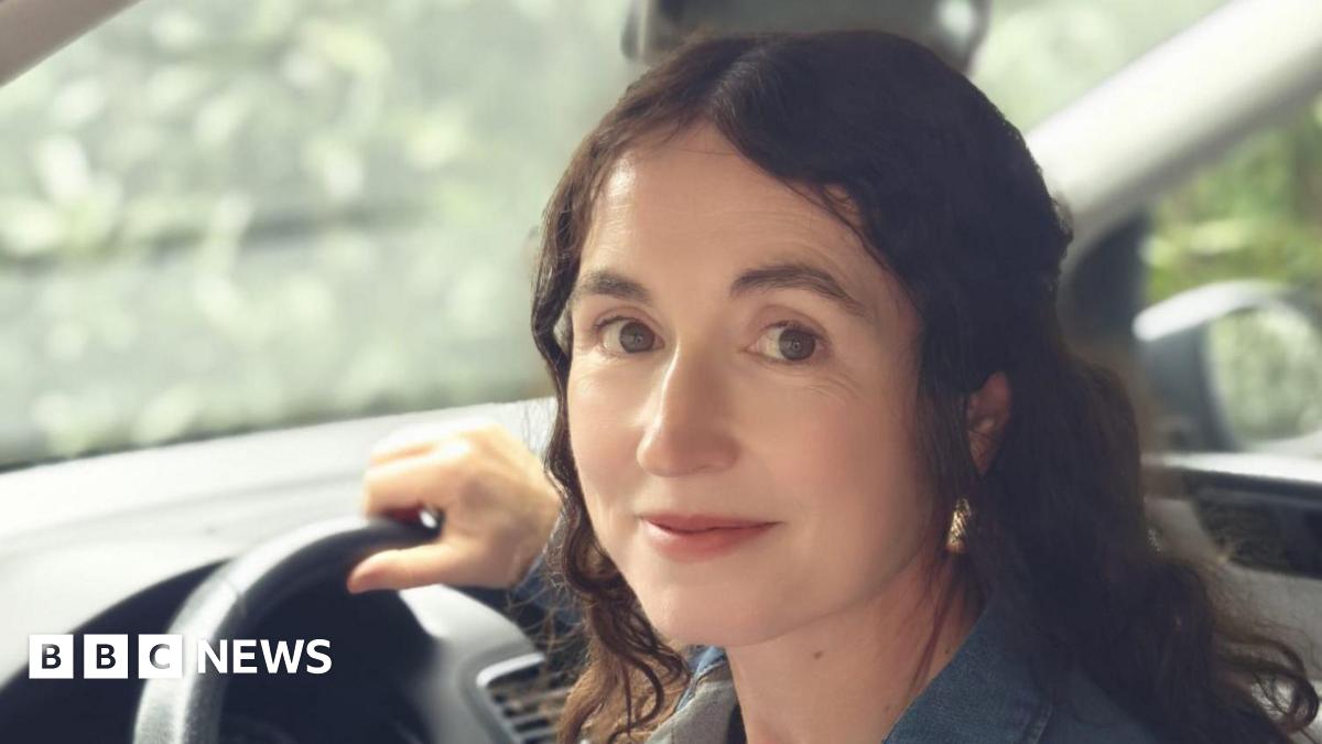 Kyle Sieniawski, laughing. Kyle has a huge smile, large black-rimmed glasses and wears a grey hooded top.